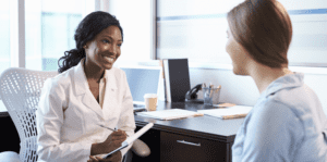 Smiling female patient having a friendly conversation with a healthcare professional in a clinical setting.